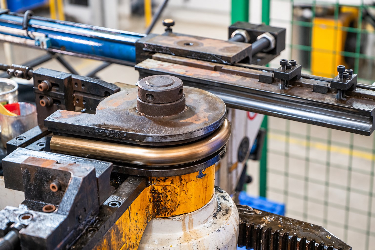 Pipe bending equipment shaping a metal tube around forming tooling